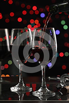 Close up pouring the red wine into the wine glass with color bokeh background in the pub bar concept