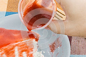 Close up pouring strawberry jam topping on the crepe cake