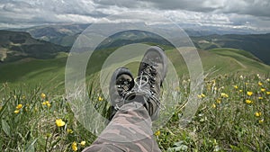 Close up POV of hiking boots of an independent male traveler on top of a mountain, looking at the view.