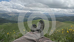 Close up POV of hiking boots of an independent male traveler on top of a mountain, looking at the view.