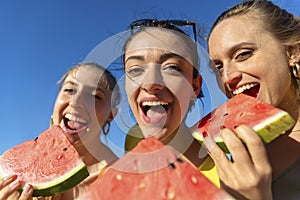 Close up pov portrait of three happy girls eating watermelon at the beach outdoors in summer time. friends having fun isolated on