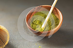 Close up powder of matcha tea is partially dissolved in hot water