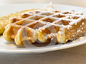 Close-up of powdered sugar belgian waffle on white plate