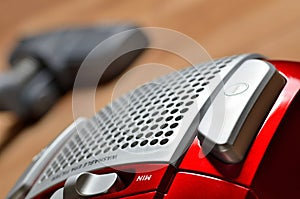 Close-up of power button of vacuum cleaner on floating floor and noozle in background - limited depth of field