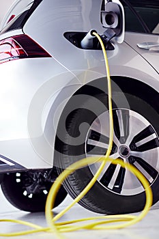 Close Up Of Power Cable Charging Environmentally Friendly Zero Emission Electric Car In Garage