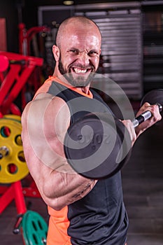 Close up of powerful muscular man doing biceps exercise with barbell at the gym
