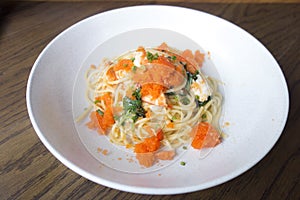 Close up of prawn chunks tossed with spaghetti chili sauce shrimp paste oil and topped with fresh shrimp roe served in white plate