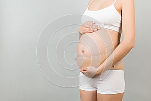 Close up of pregnancy bandage dressed on pregnant woman in underwear for reducing backpain at gray background with copy space.