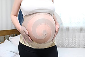 Close-up of a pregnant belly in a bandage to support pregnant. Orthopedic abdominal support belt concept