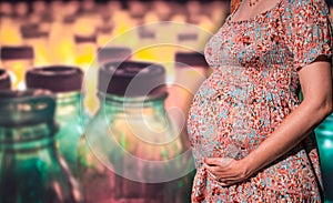 Close-up of a pregnant belly with a blurred plastic bottles on the background