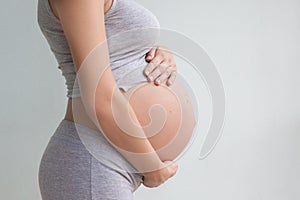 Close-up of a pregnant belly. A pregnant woman holds her hands in her stomach. Third trimester. Pregnancy. Mother`s day. Waiting