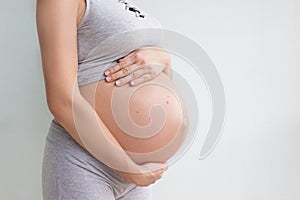 Close-up of a pregnant belly. A pregnant woman holds her hands in her stomach. Third trimester. Pregnancy. Mother`s day. Waiting