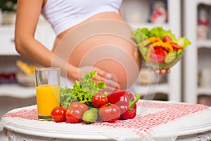 Close-up of a pregnant belly. Women's Health, fortified food. Fresh vegetables, diet and figure