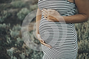 Close up of pregnant people. Mature lady 45 years old with pregnant belly in outdoor portrait. Future mommy newborn lifestyle.