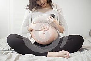 Close up of Pregnant woman applying cream at her belly