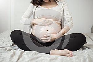 Close up of Pregnant woman applying cream at her belly