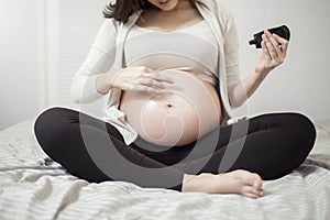 Close up of a Pregnant woman applying cream at her belly