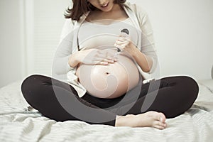 Close up of Pregnant woman applying cream at her belly