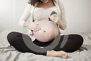 Close up of Pregnant woman applying cream at her belly