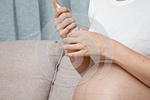 Close up of pregnant woman applying moisturizing cream on her belly. Concept of pregnancy and skin care. Pregnant woman