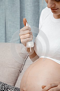 Close up of pregnant woman applying moisturizing cream on her belly. Concept of pregnancy and skin care. Pregnant woman