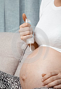 Close up of pregnant woman applying moisturizing cream on her belly. Concept of pregnancy and skin care. Pregnant woman