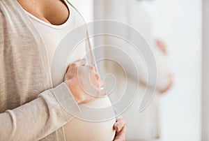 Close up of pregnant woman belly at mirror