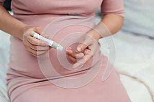 Pregnant woman checking blood sugar level by herself at home. gestational diabetes concept