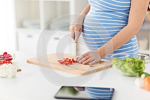 Close up of pregnant woman cooking food at home