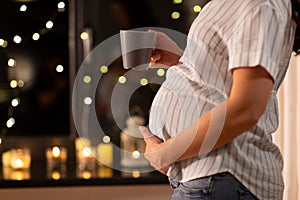 close up of pregnant woman drinking tea at home