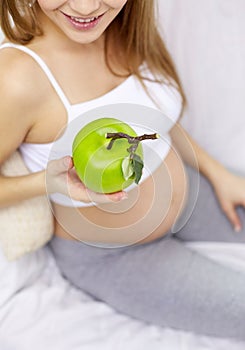 Close up of pregnant woman eating apple at home