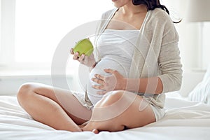 Close up of pregnant woman eating apple at home