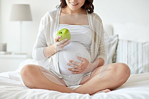 Close up of pregnant woman eating apple at home