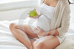 Close up of pregnant woman eating apple at home