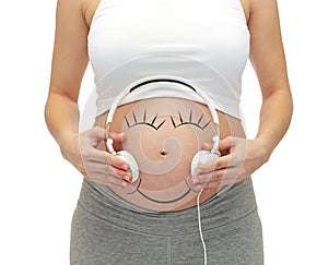 Close up of pregnant woman and headphones on tummy