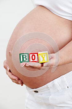 Close Up Of Pregnant Woman Holding Blocks Spelling BOY