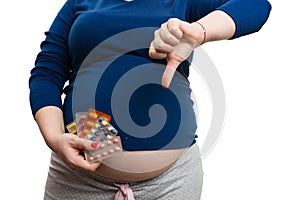 Close-up of pregnant woman holding medicines and making unlike gesture with hand