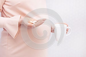 Close-up of pregnant woman holding a pill, vitamins. The concept of pregnancy
