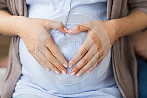 Close up of pregnant woman making heart on belly