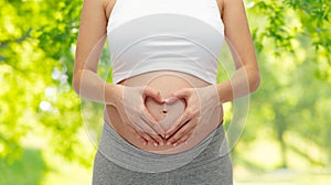 Close up of pregnant woman making heart gesture