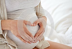 Close up of pregnant woman making heart gesture