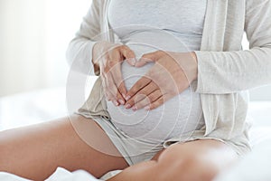 Close up of pregnant woman making heart gesture