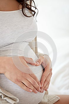 Close up of pregnant woman making heart gesture