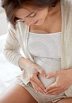 Close up of pregnant woman making heart gesture