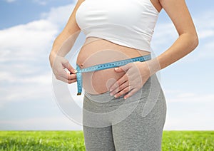 Close up of pregnant woman measuring her tummy