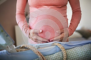 Close-up of pregnant woman preparing for baby, stroking her belly.