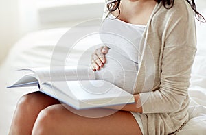 Close up of pregnant woman reading book at home