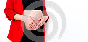 Close Up pregnant woman in red suit forming a heart-shape with her hands over her stomach or belly isolated on white background