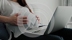 Close up of Pregnant Woman Resting on a Sofa at Home and Working Remotely with Laptop Computer Using Online Technology.