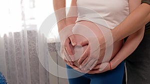 Close up of pregnant woman\'s belly, man and woman putting hands on belly.